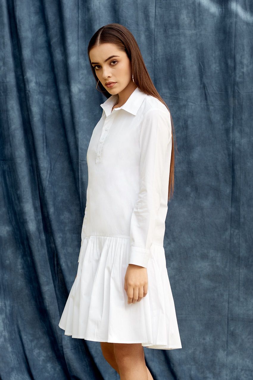 White drop waist shirt dress with pleated details and hemmed cuffs