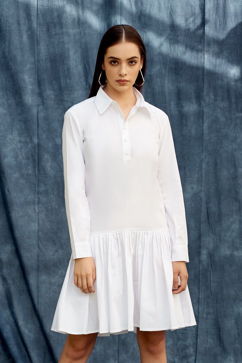 White drop waist shirt dress with pleated details and hemmed cuffs