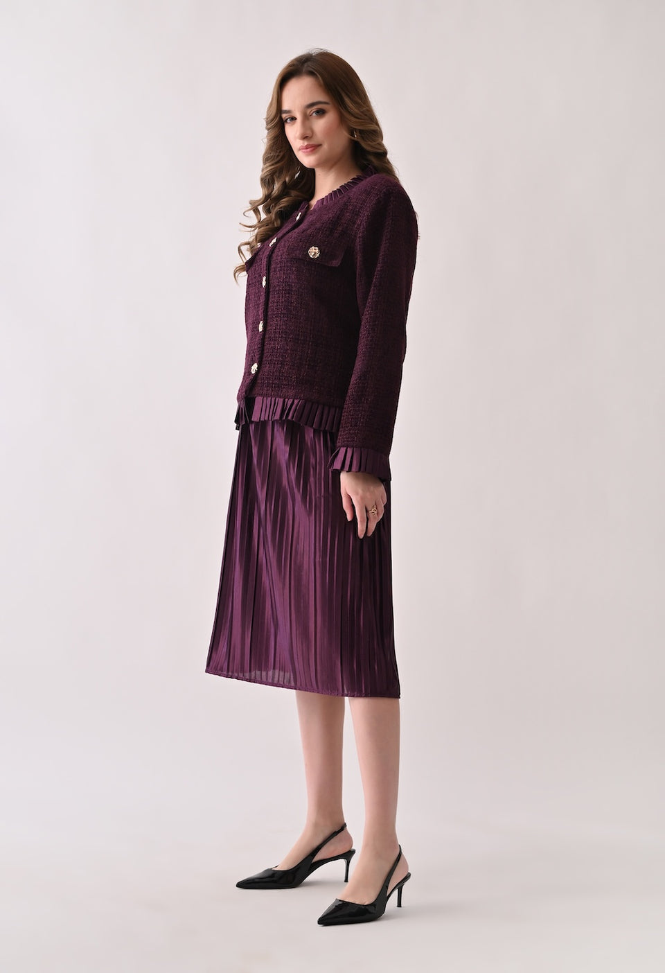 Wine colored tweed jacket with gold buttons and ruffle details paired with a matching pleated midi skirt