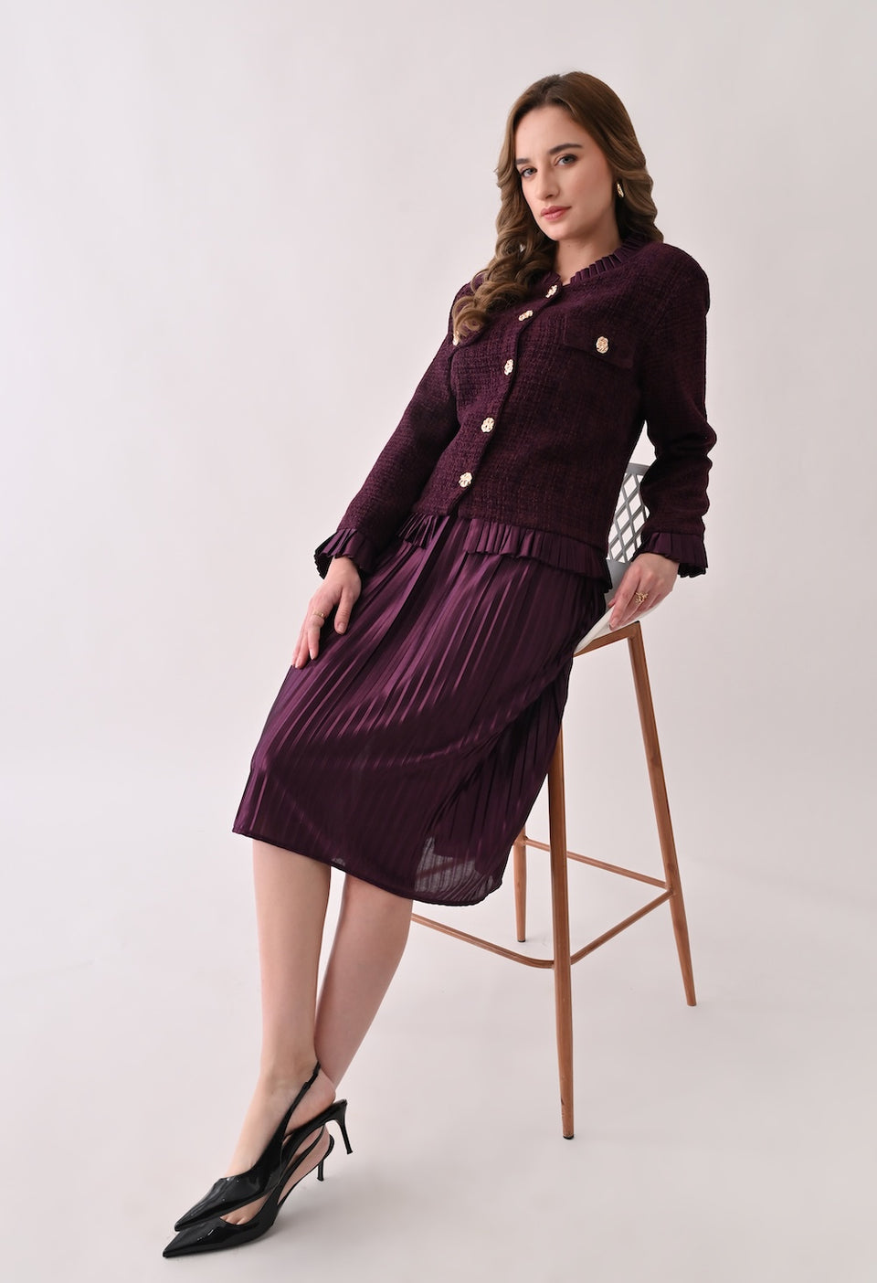 Wine colored tweed jacket with gold buttons and ruffle details paired with a matching pleated midi skirt