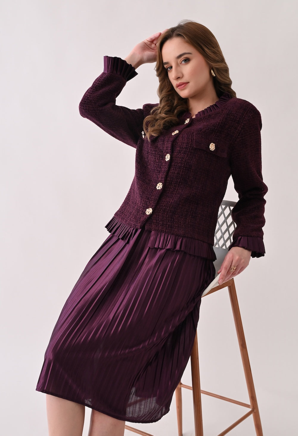 Wine colored tweed jacket with gold buttons and ruffle details paired with a matching pleated midi skirt