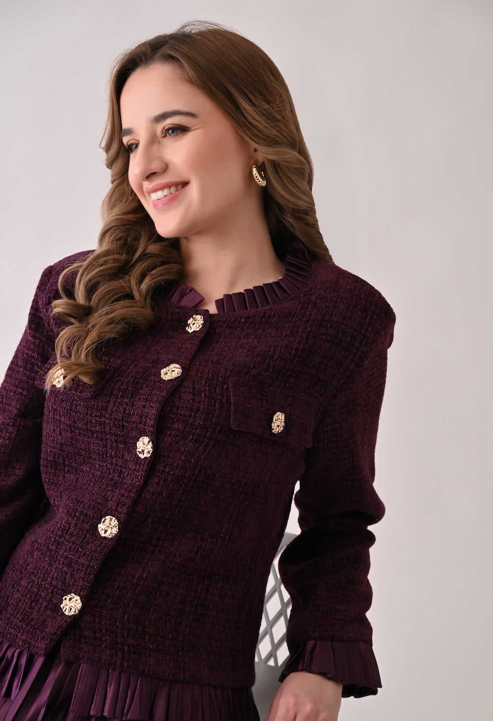 Wine colored tweed jacket with gold buttons and ruffle details paired with a matching pleated midi skirt