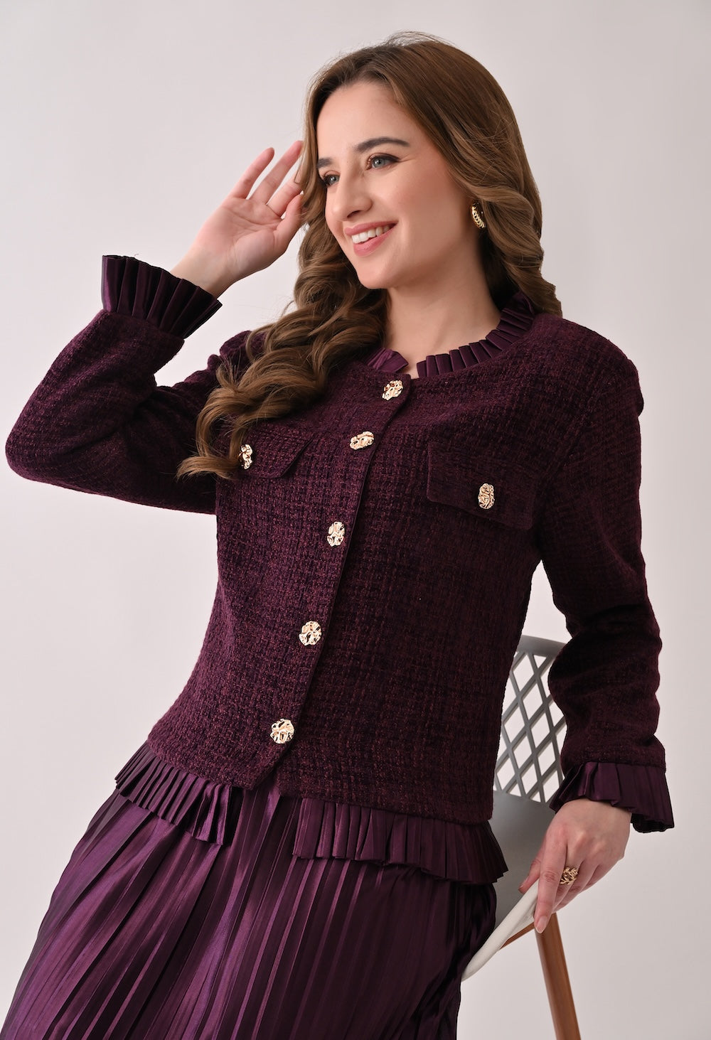 Wine colored tweed jacket with gold buttons and ruffle details paired with a matching pleated midi skirt