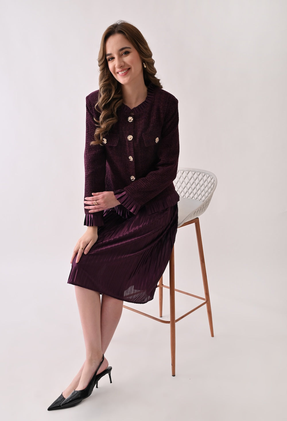 Wine colored tweed jacket with gold buttons and ruffle details paired with a matching pleated midi skirt
